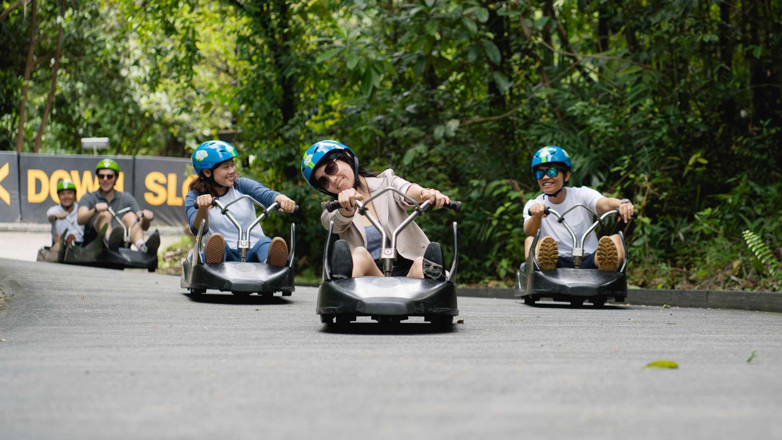 A group of people ride around a corner on The Singapore Luge.