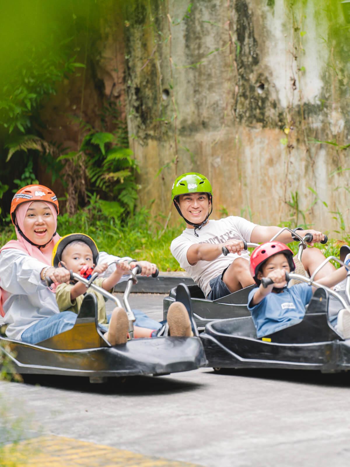 A family group rides down the tracks together with children riding in the same cart as an adult and one riding by himself.