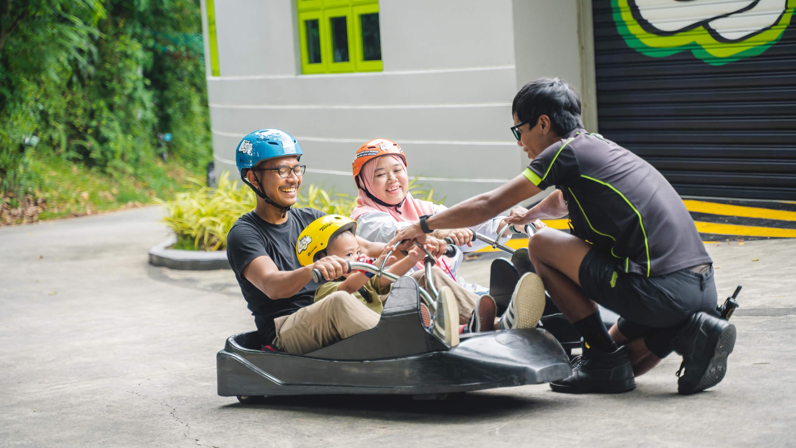 A Skyline Luge Singapore employee teaches a family how to use the Luge carts safely.