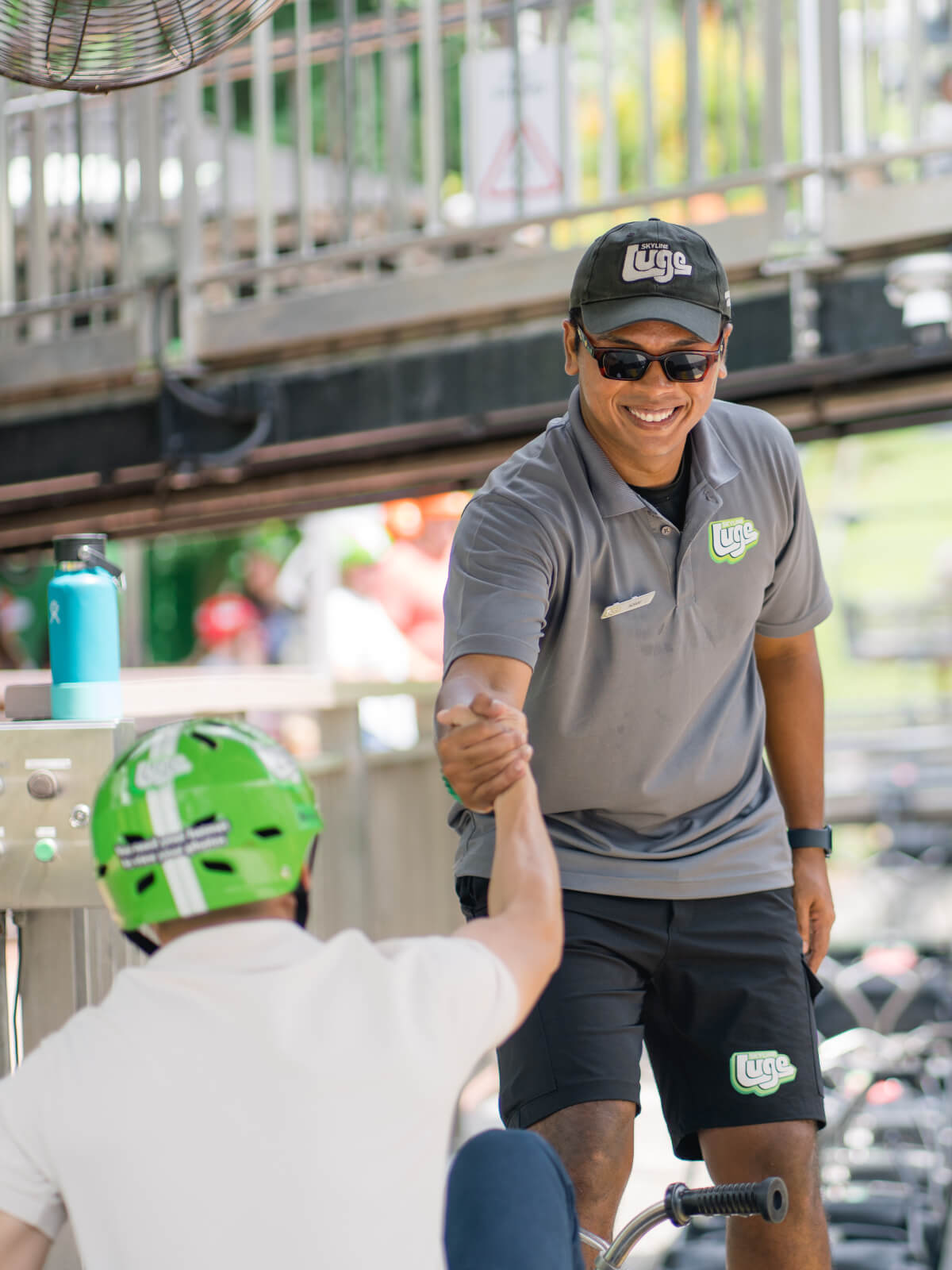 A Luge employee gives a customer a hand out of his Luge cart.