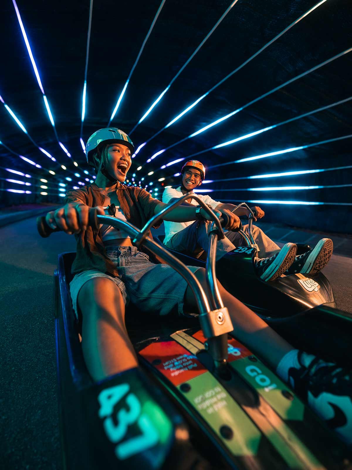 Skyline Luge Singapore A Pair of youth on the Luge carts riding through the tunnel feature enjoying the Night Luge Ride the Beat experience