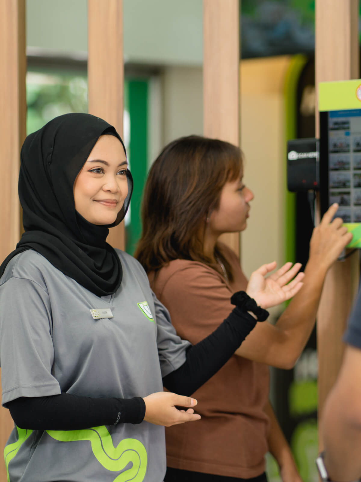 A ticketing employee helps customers at Skyline Luge Singapore select their photos.