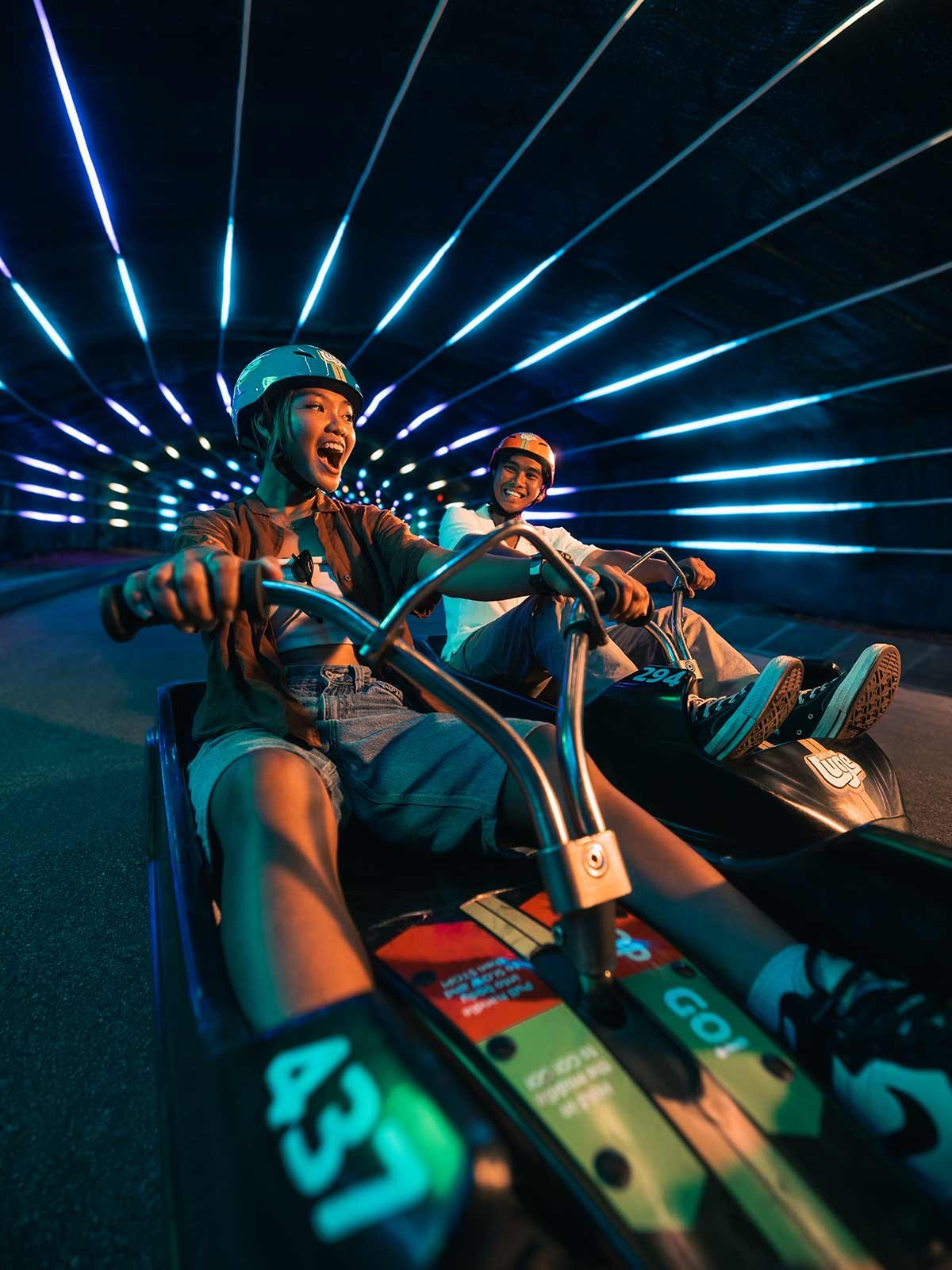 Skyline Luge Singapore A Pair of youth on the Luge carts riding through the tunnel feature enjoying the Night Luge Ride the Beat experience