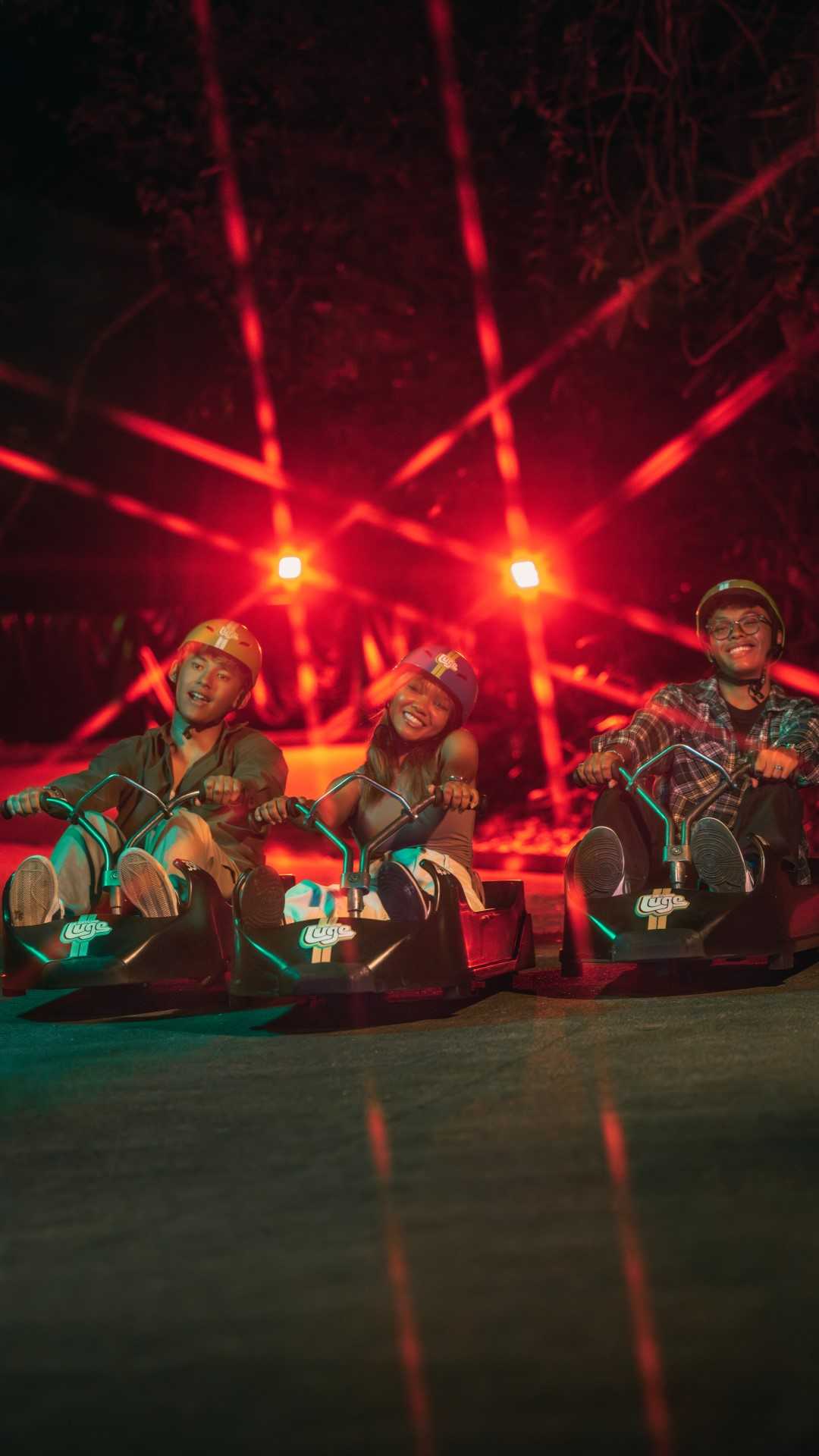 Three friends ride down the tracks together on the Singapore Night Luge.