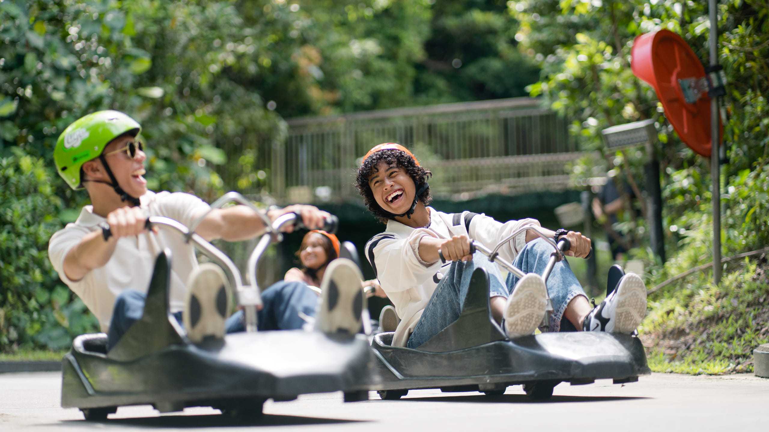 Two friends look at each other and laugh whilst riding the Singapore Luge.