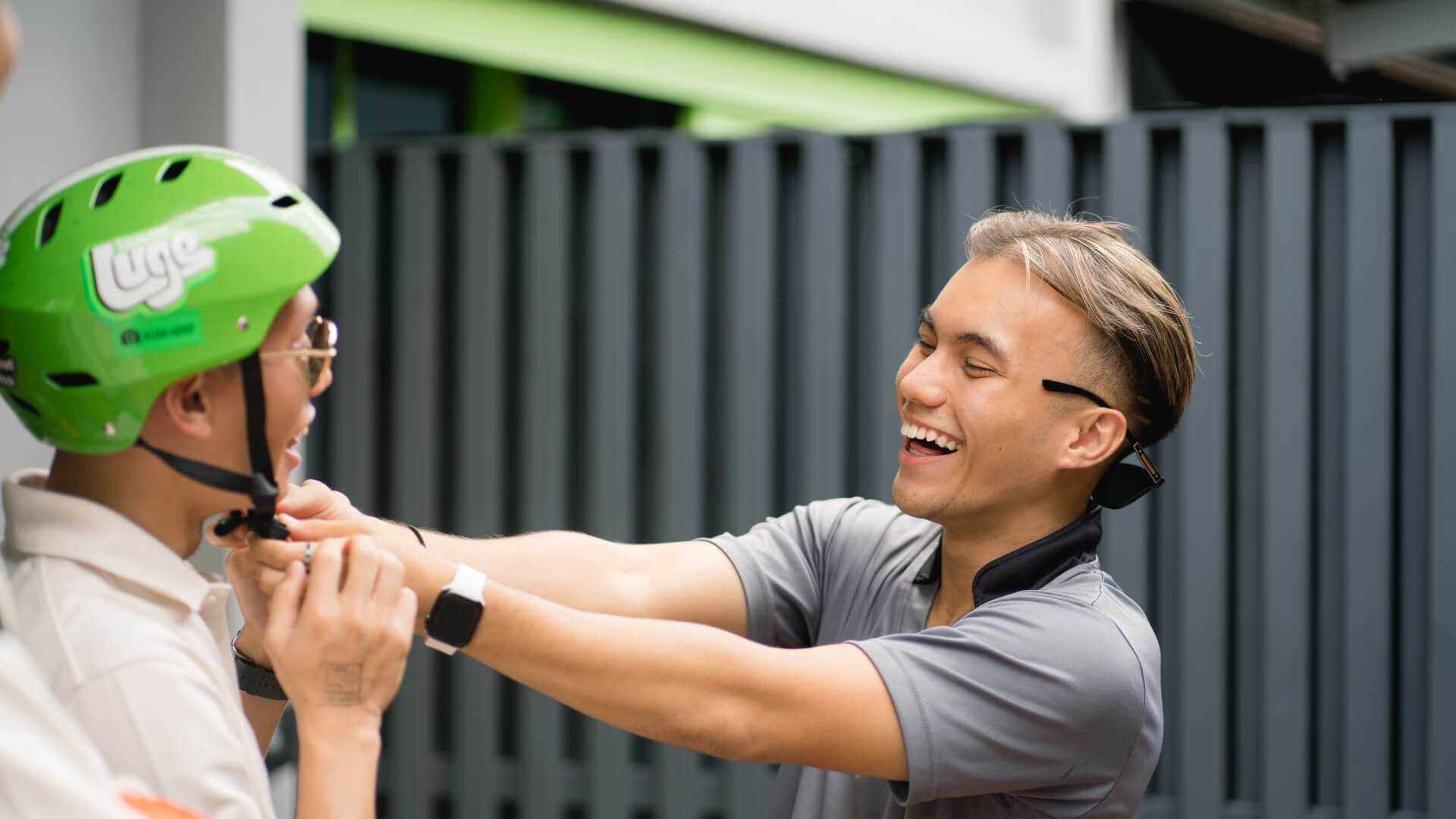 A Luge employee helps a customer fasten his helmet.