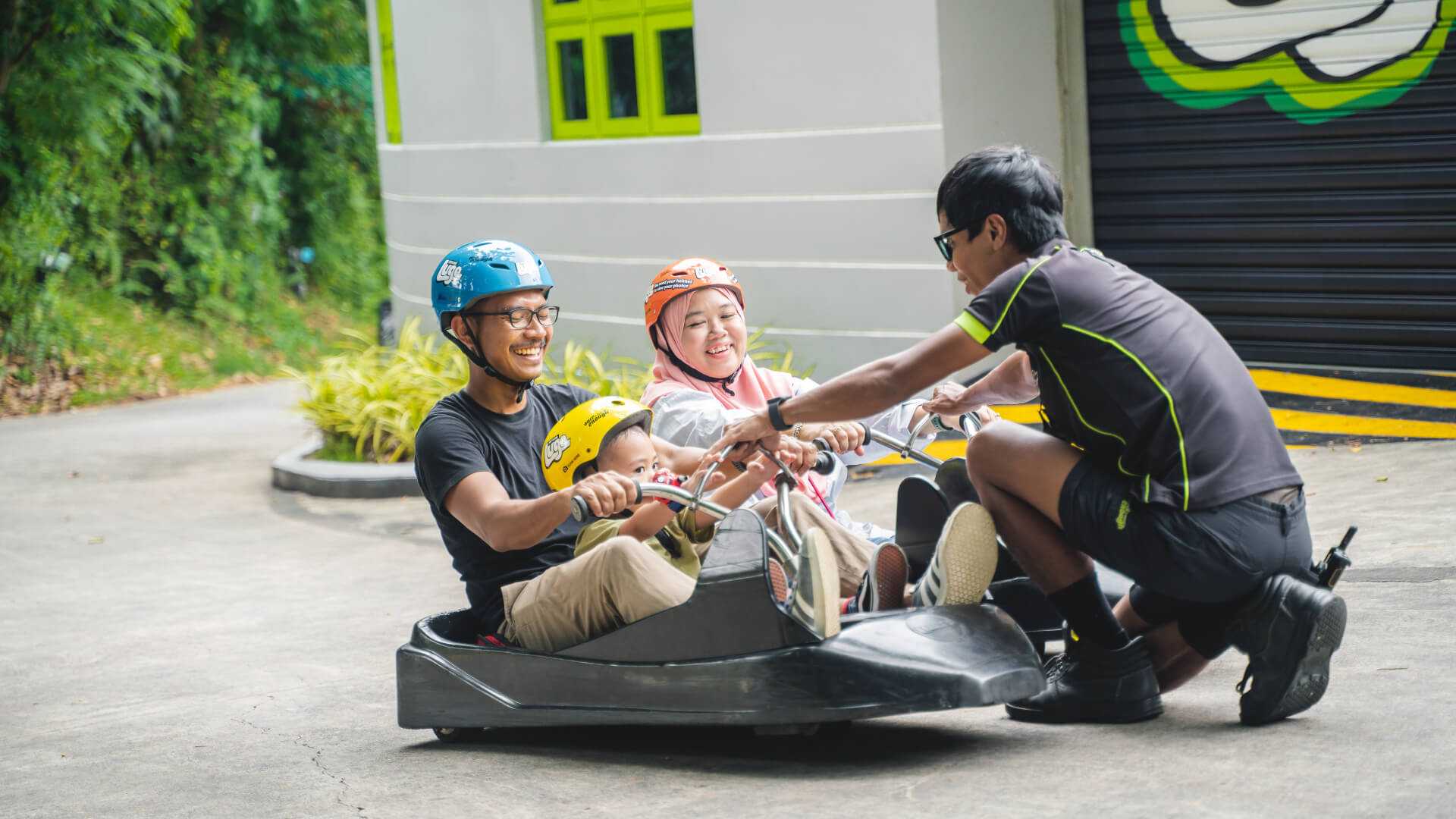 A Skyline Luge Singapore employee teaches a family how to use the Luge carts safely.
