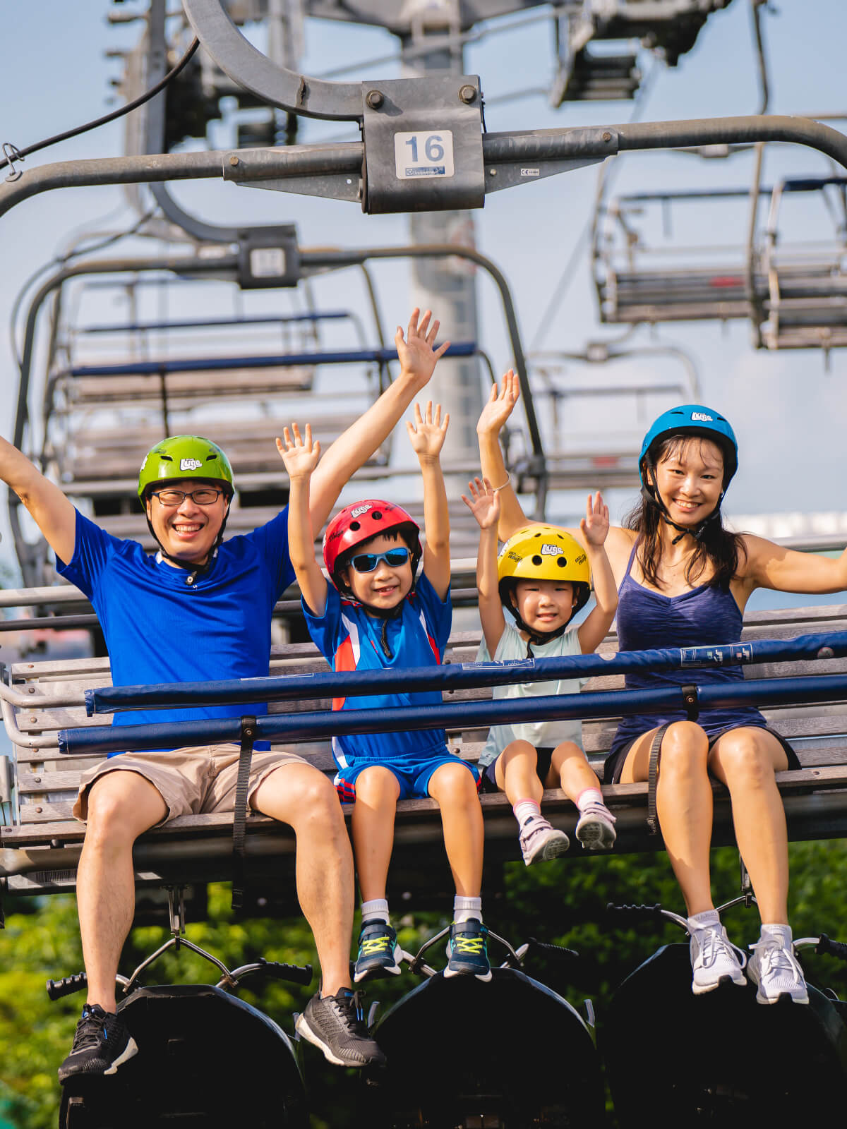 A family with two small kids rides the Skyride chairlift together.